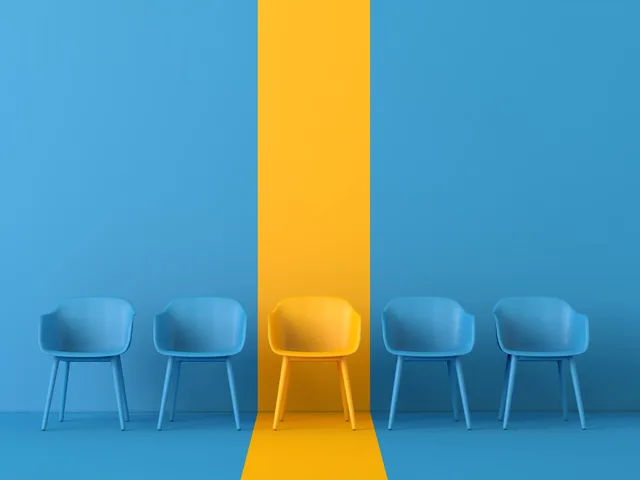 Yellow chair standing out among blue chairs, representing differentiation, innovation, and competitive advantage in AI strategy.
